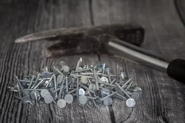 A hammer beside nails for post California Roofing Laws: How many layers of Shingle?