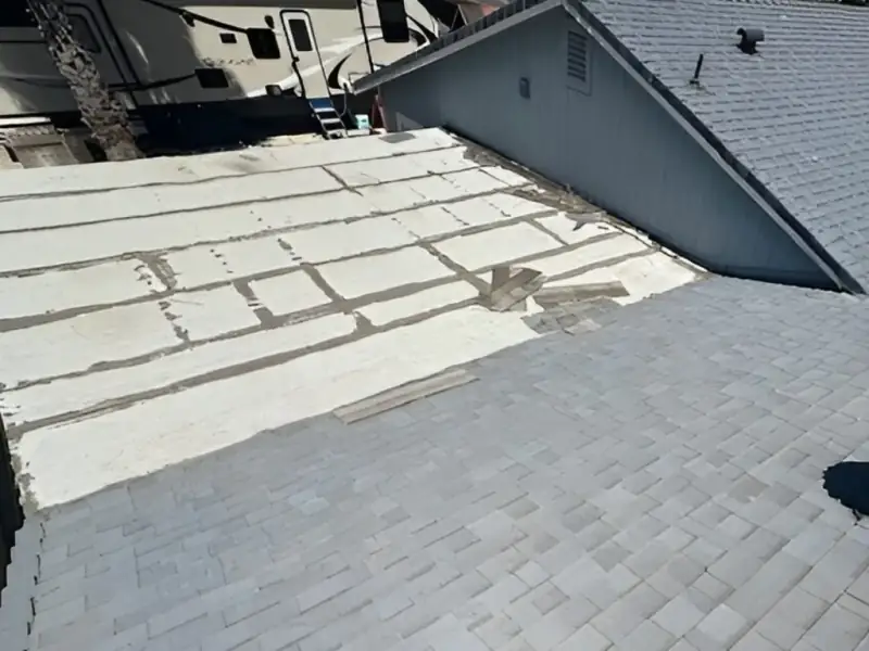 Aged low-slope white roof surface, patched and cracked at the seams