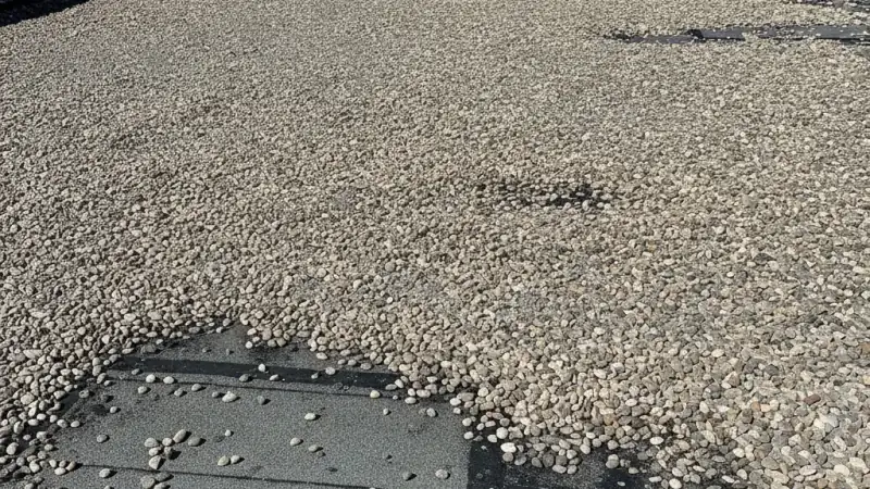 Built-up roof surface with layered felts and gravel ballast on a commercial building