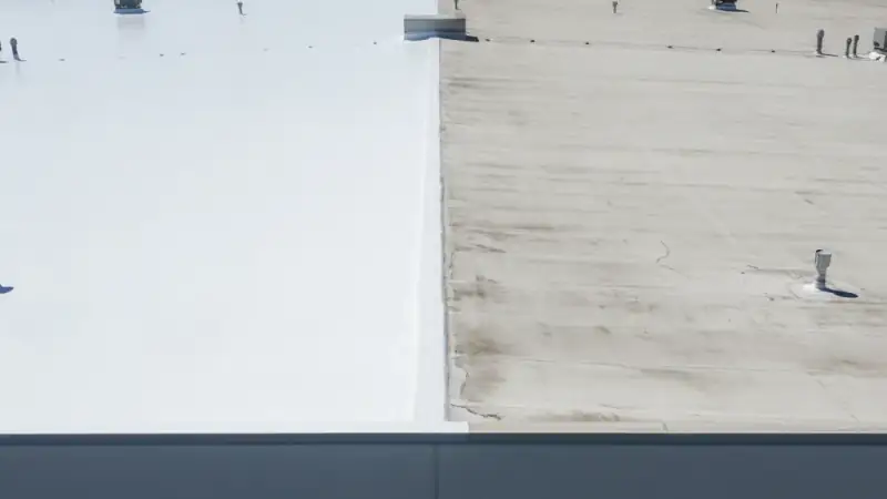 Fresh white reflective roof coating rolled across a commercial low-slope roof