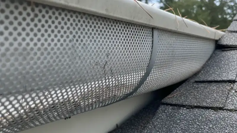 Perforated metal screen gutter guard installed over a residential gutter