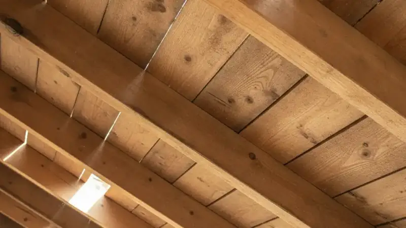 Interior underside of a residential roof in an attic showing rafters and decking