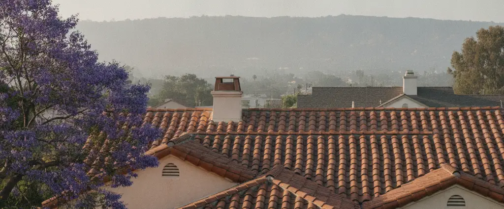 Well-maintained residential rooftops in West Los Angeles, Los Angeles County, California, with hazy coastal hills beyond