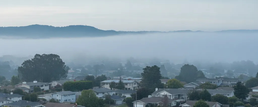 Well-maintained residential rooftops in Milpitas, Santa Clara County, California, with rolling hills and coastal haze