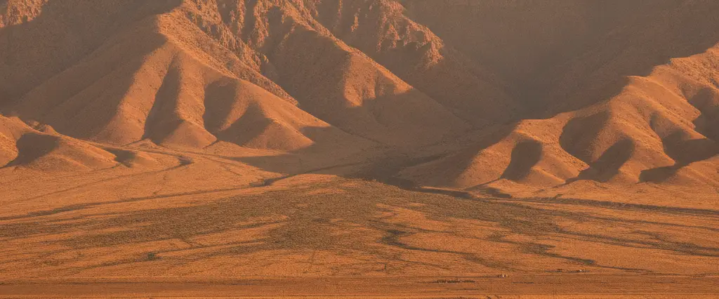 Kern County agriculture and oil-pump plains meeting the Tehachapi mountains with wind farms on golden ridges