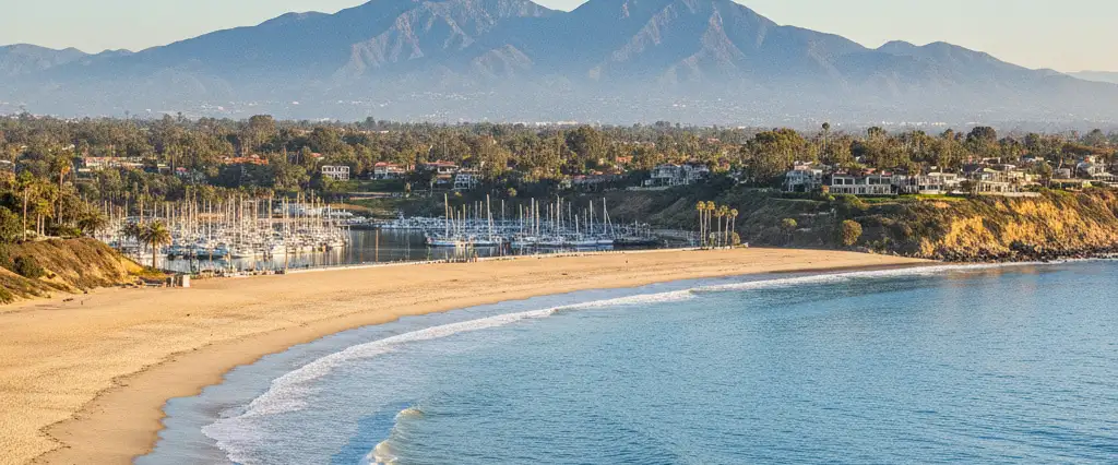 Orange County sunny surf beach and yacht harbor with the Saddleback ridgeline of the Santa Ana Mountains