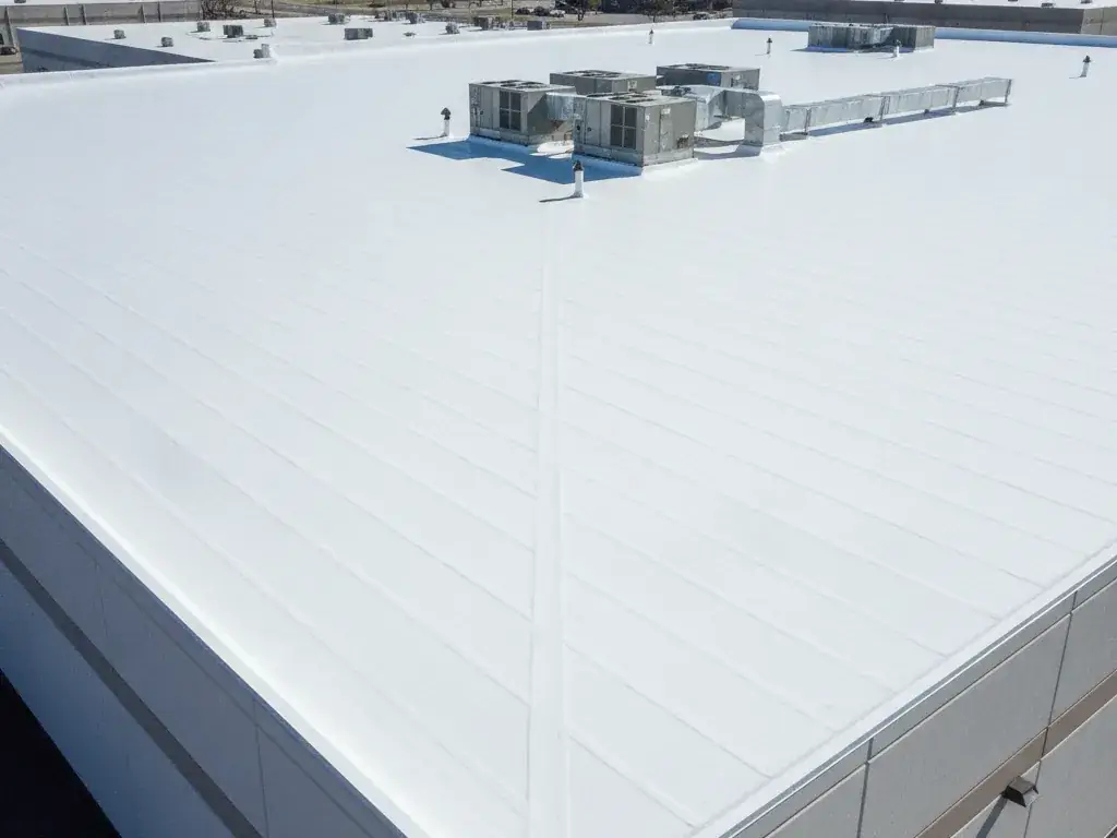 Flat commercial building roof with a repaired white TPO membrane and rooftop units