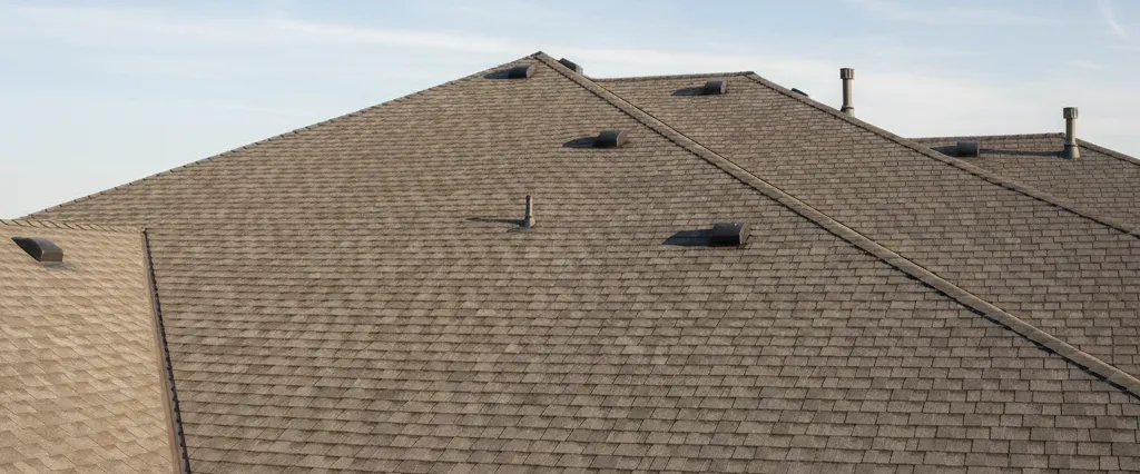 Residential rooftop showing repaired flashing and sealed penetrations under a clear sky, mid leak repair