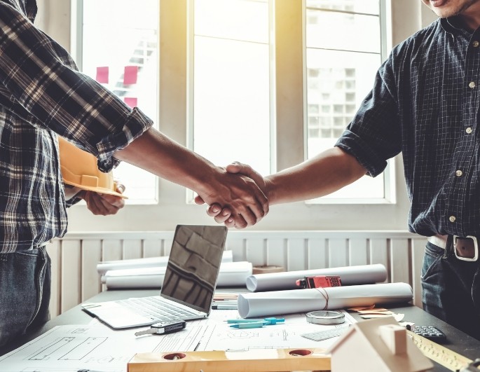 a contractor and his client shaking hands after an agreement