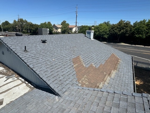 A damaged shingle roof that has missing shingles due to wind damage