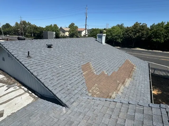 A damaged shingle roof that has missing shingles due to wind damage